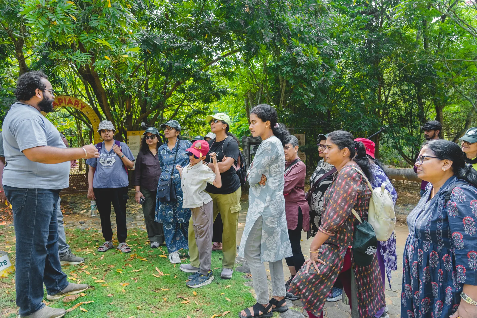 A naturalist briefing a group of walkers beneath tall shade trees